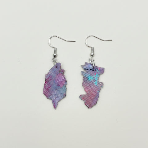 Pair of pink and purple earrings on a wooden surface