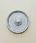 Ceramic incense burner with blue rim on a wooden surface