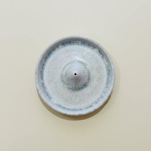Ceramic incense burner with blue rim on a wooden surface