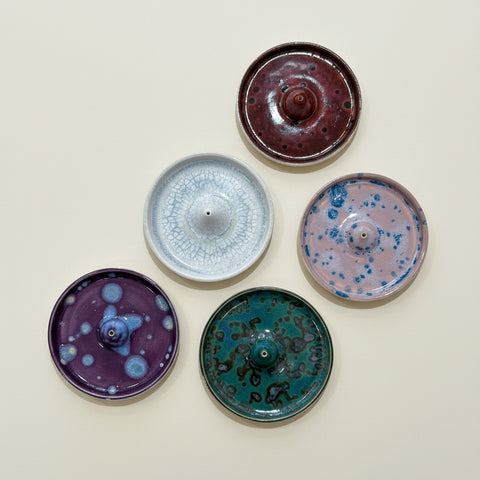 Five ceramic incense burners with different designs on a wooden surface
