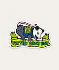 Sticker with an illustration of a creature and text on a wooden surface