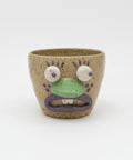 Ceramic cup with a face design on a wooden surface.
