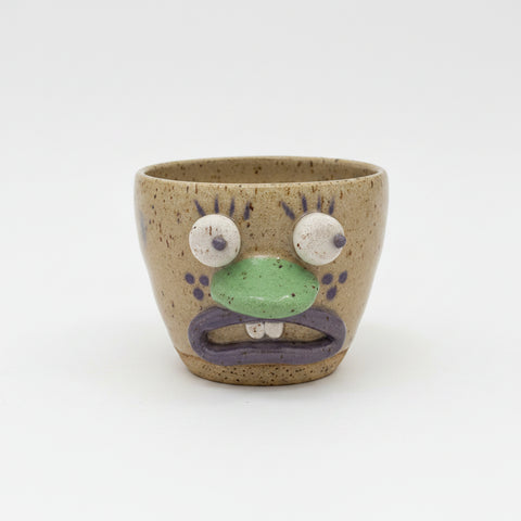 Ceramic cup with a face design on a wooden surface.