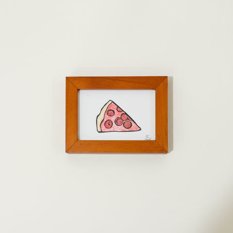 Framed drawing of a slice of pizza on a wooden surface