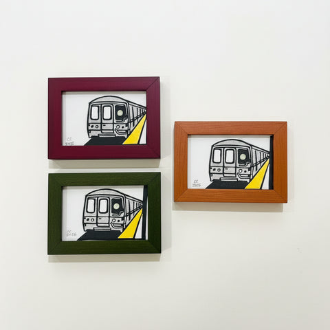 Three framed illustrations of a train on a wooden surface