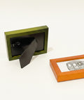 Small green picture frame on a wooden surface with another frame displaying a drawing of a train.
