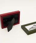 Two picture frames on a wooden surface, one red and one black with a design.
