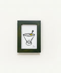 Framed drawing of a cocktail on a wooden surface