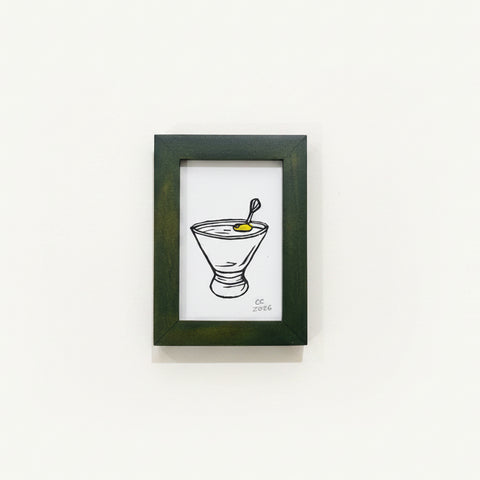 Framed drawing of a cocktail on a wooden surface