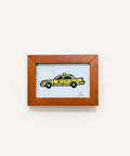 Framed artwork of a yellow taxi on a white background