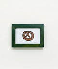 Framed artwork of a pretzel on a wooden surface