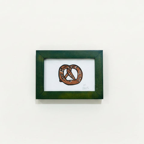 Framed artwork of a pretzel on a wooden surface