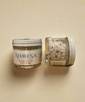 Two jars of salt on a wooden surface.
