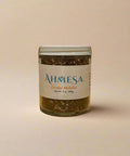 Jar of Ahmesa za'atar mufalfal seasoning on a wooden surface. 