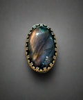 Ring with an oval stone and decorative band on a wooden surface