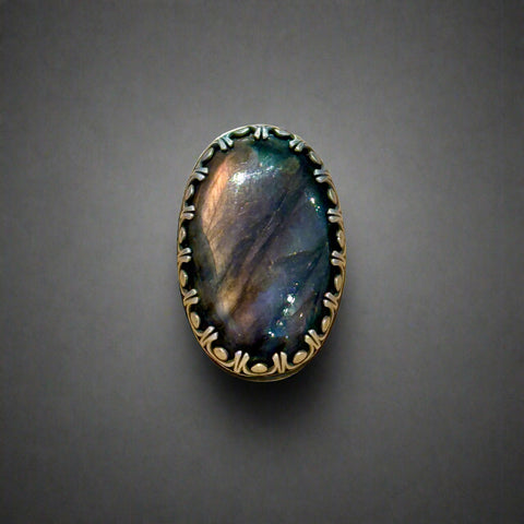 Ring with an oval stone and decorative band on a wooden surface