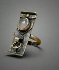 Silver ring with a central stone on a wooden surface