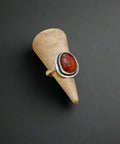 Silver ring with a red stone on a beige cone against a wooden background
