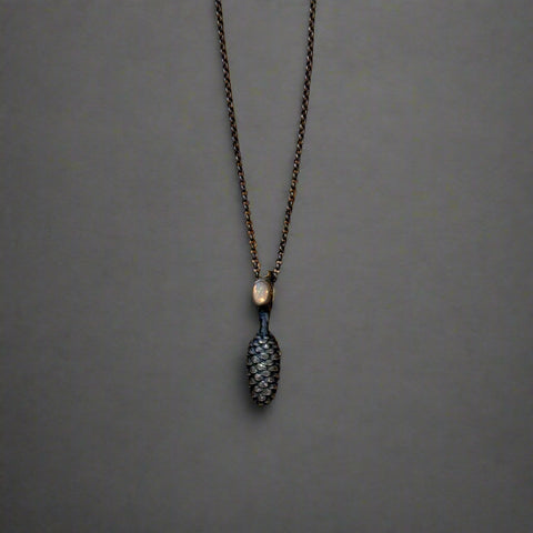 Necklace with a pine cone pendant on a wooden surface