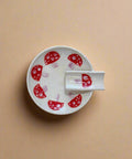 White ceramic dish with red mushroom design on a wooden surface