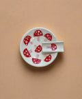 White ceramic dish with red mushroom design on a wooden surface