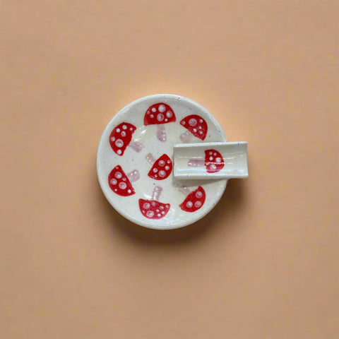 White ceramic dish with red mushroom design on a wooden surface