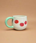 Mug with red apple design on a cardboard surface with a blue curtain background