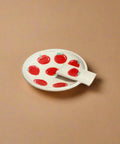 Small white plate with red apple design on a cardboard surface