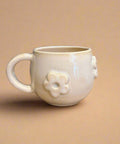 White ceramic mug with floral design on a beige background