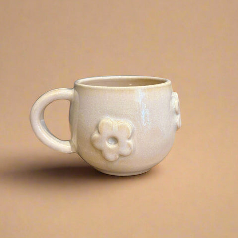 White ceramic mug with floral design on a beige background