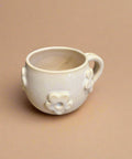 White ceramic mug with floral designs on a tan surface