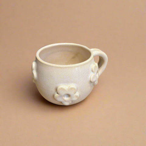 White ceramic mug with floral designs on a tan surface