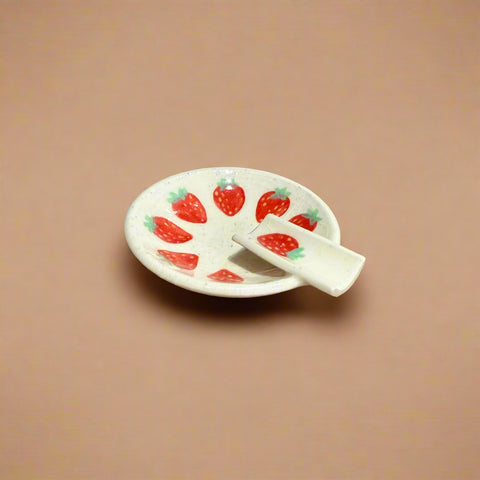 Small ceramic plate with strawberry design on a cardboard surface