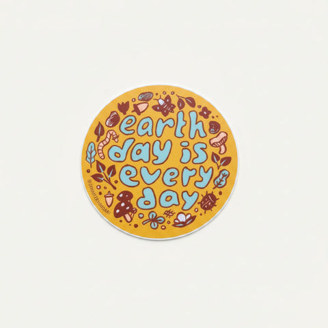Round sticker with 'earth day is every day' text on a wooden surface