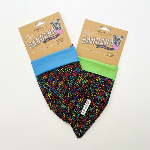 Two pet bandanas by MomeMade displayed on a light wood surface. One bandana is light blue with a multicolor alphabet print, and the other is lime green with the same multicolor alphabet print.