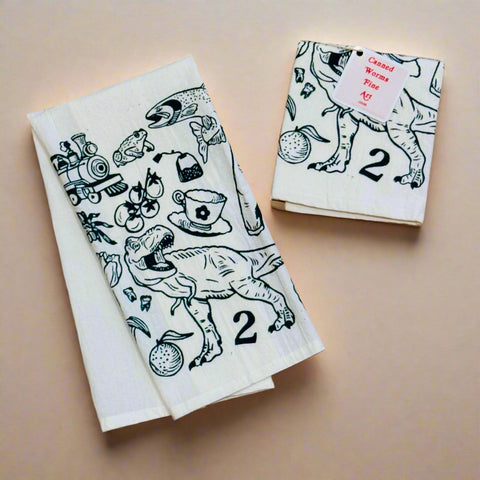 Two white towels with dark green illustrations