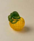 Glass pumpkin with green stem on a wooden table in a store setting