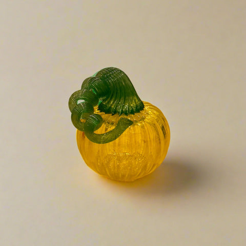 Glass pumpkin with green stem on a wooden table in a store setting