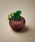 Glass pumpkin figurine on a wooden surface with a store interior in the background