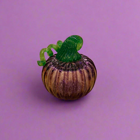 Glass pumpkin figurine on a wooden surface with a store interior in the background