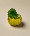 Green glass pumpkin on a wooden table with store interior in the background