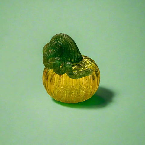 Green glass pumpkin on a wooden table with store interior in the background