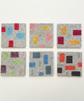 Six square ceramic coasters with abstract geometric patterns in various colors, arranged in a 2x3 grid on a light wood surface.