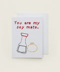 A white greeting card with the phrase 'You are my soy mate.' in red handwritten-style text, plus simple drawings of a soy sauce bottle and a dumpling.