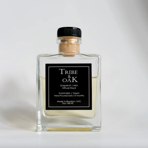 Clear glass diffuser bottle with black label featuring 'Tribe & Oak' on a white background