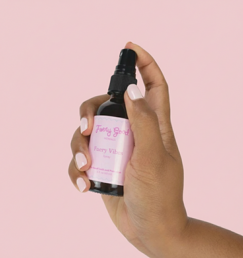 Hand holding a bottle labeled 'Fairy Vibes' against a white background