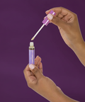 Hand holding a purple dropper with a white background