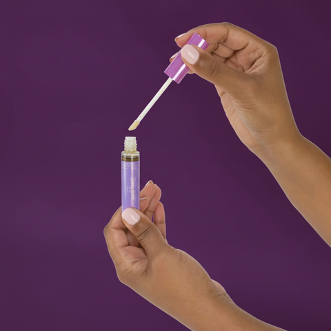 Hand holding a purple dropper with a white background