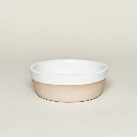 Ceramic bowl with white top and beige bottom on a tan background