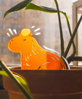 Orange cat-shaped lamp in a pot with a blurred indoor background